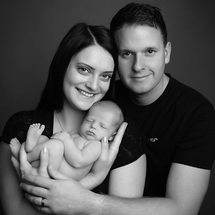 cute baby boy with family by photographer in Milton Keynes