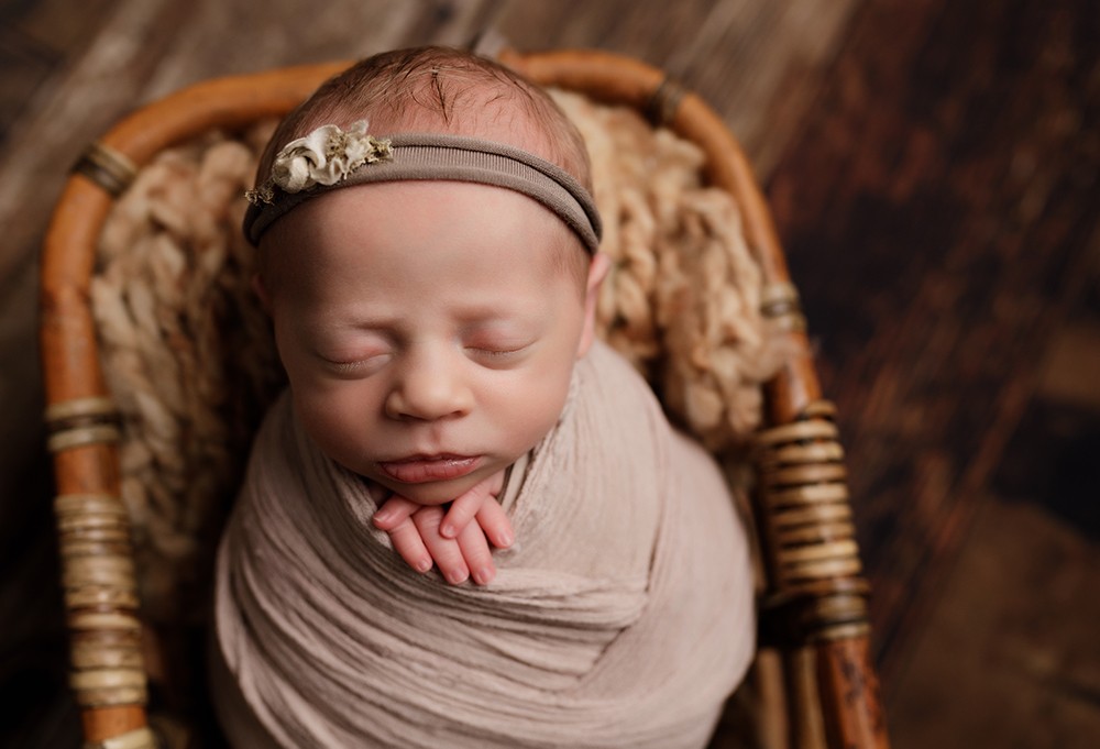 baby girl asleep on hands in a barrel by Newborn Photographer Milton Keynes