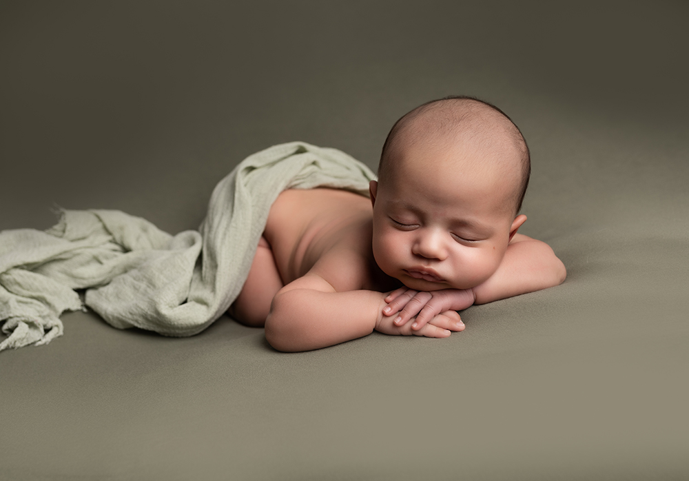 sleeping newborn baby boy with tartan blanket in a review of a newborn photographer