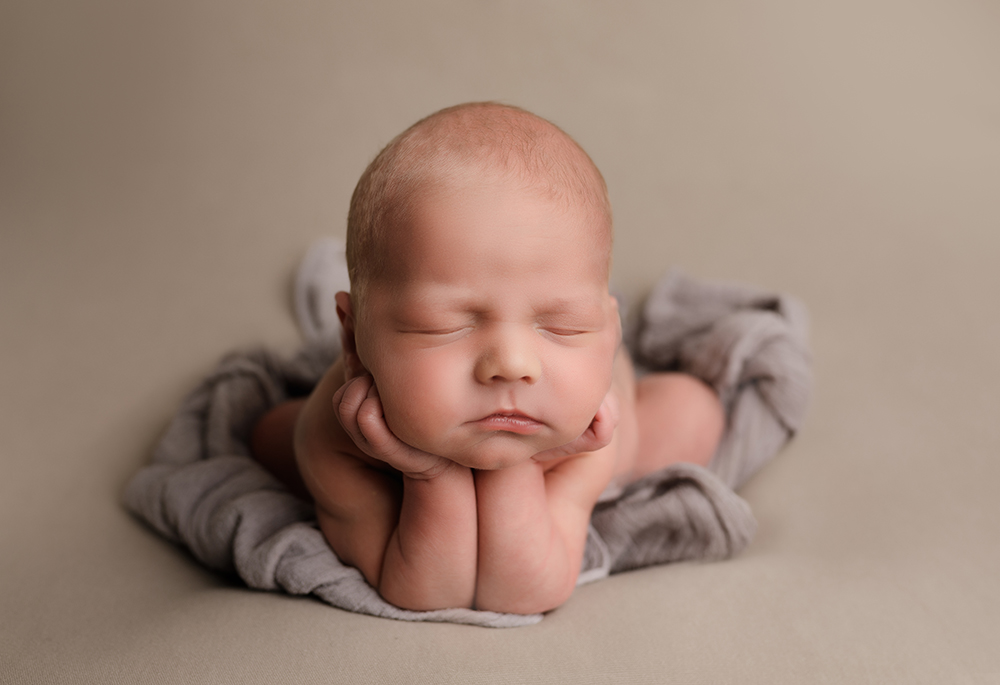baby boy in froggy pose on beige blanket photographed by newborn photographer Milton Keynes