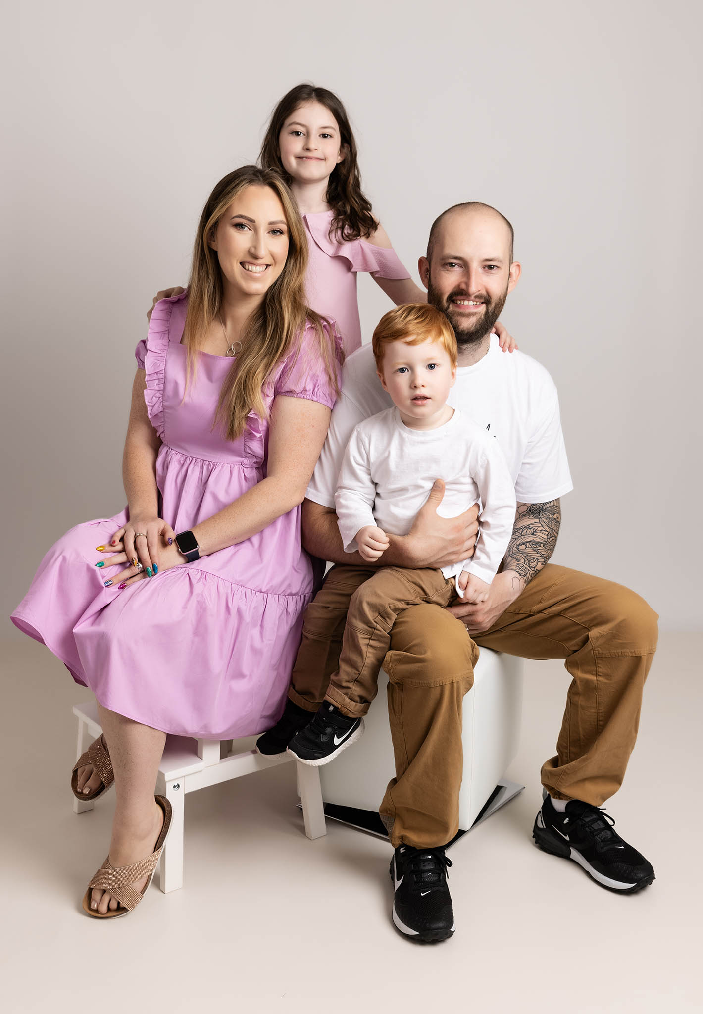 Family of two parents and two children on a cream background photographed by family photographer in milton keynes and northampton
