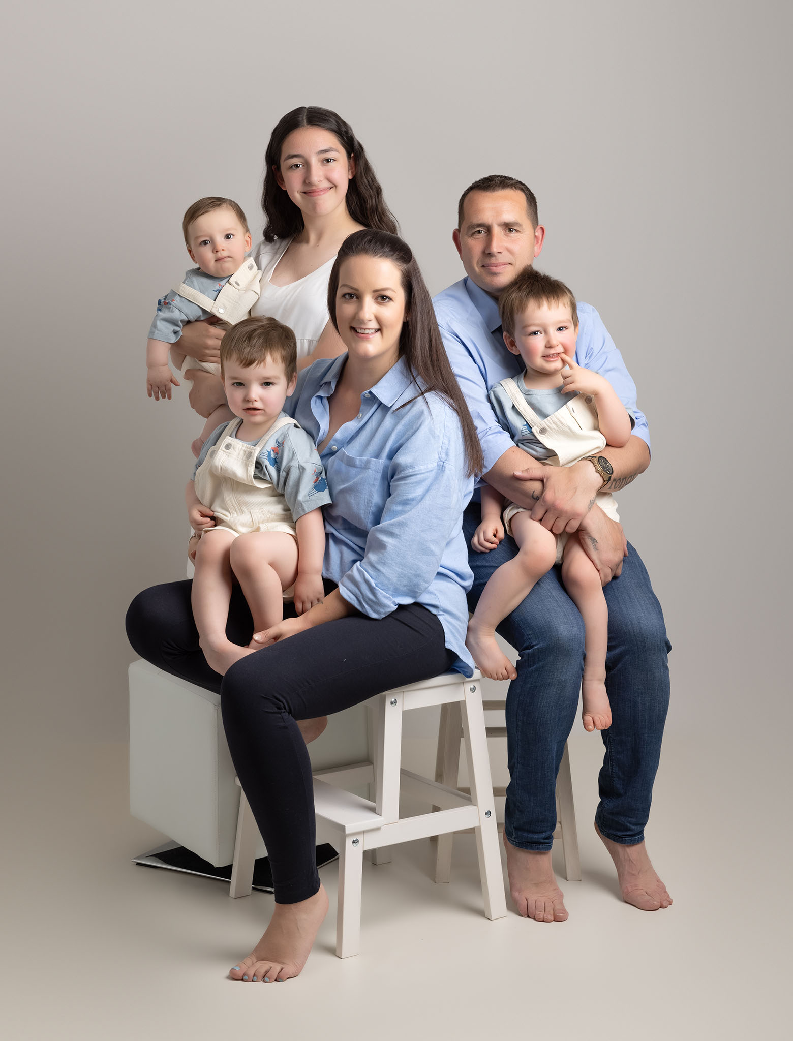 family with three baby boys in blue shirts photographed by Newborn Photographer Milton Keynes